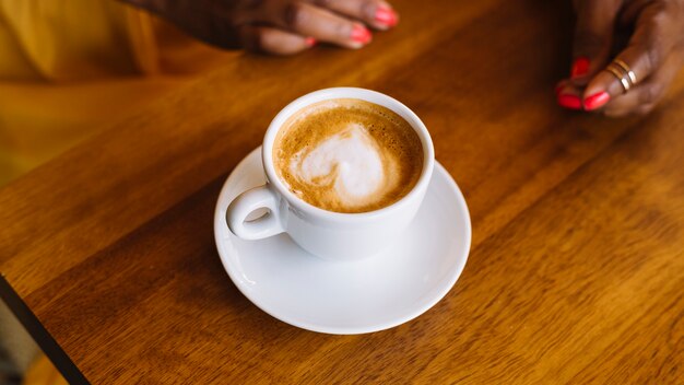 Xícara de café cappuccino com arte de latte de forma de coração na superfície de madeira