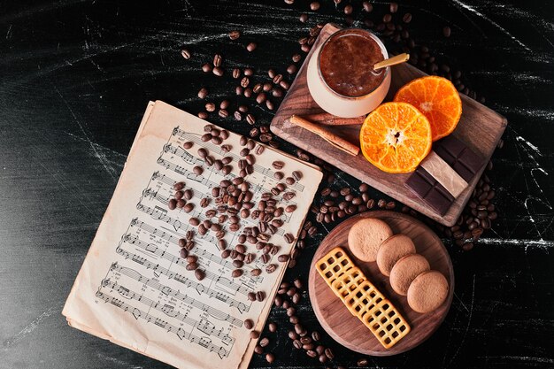 Xícara de café com fatias de laranja e biscoitos.