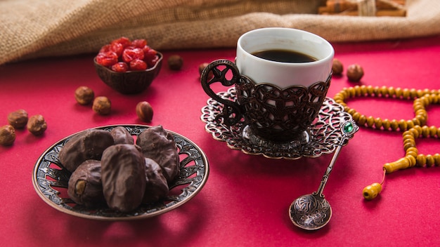 Xícara de café com frutas de datas e miçangas na mesa