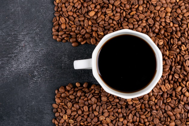 xícara de café com grãos de café na mesa escura