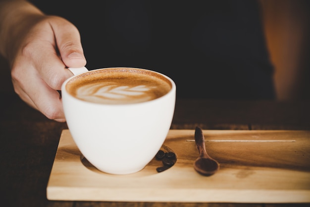 Xícara de café com leite na mesa de madeira no café café