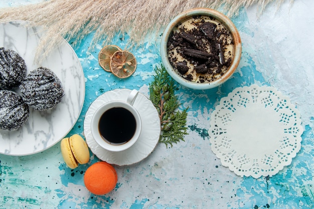 Xícara de café de vista superior com sobremesa de biscoito de macarons franceses e bolos de chocolate no fundo azul Bolo assar biscoito chocolate doce cor de açúcar