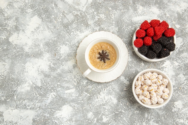 Xícara de café delicioso cappuccino com frutas na superfície branca