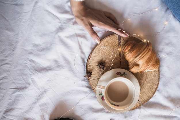 Xícara de café e croissant na bandeja de madeira