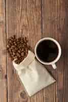 Foto grátis xícara de café e saco de pano com grãos de café