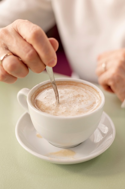 Foto grátis xícara de café fêmea sênior de alto ângulo