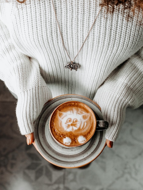 Xícara de café fresca nas palmas das mulheres