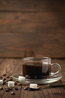 Xícara de café preto na mesa de madeira.