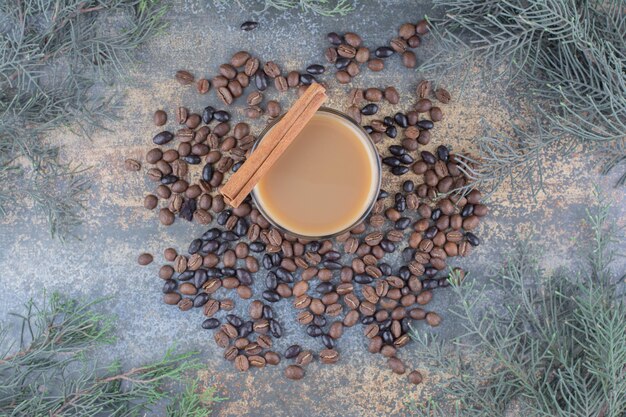 Xícara de café quente com pau de canela e grãos de café sobre fundo de mármore. Foto de alta qualidade