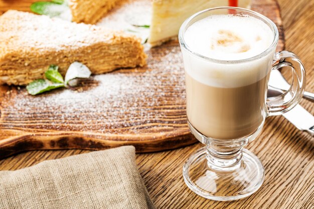 Xícara de cappuccino com café com leite em fundo de madeira. linda espuma, taça de cerâmica verde.