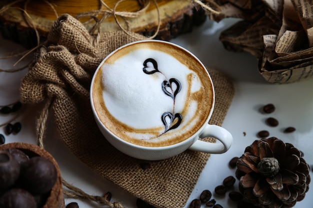 Xícara de capuccino de vista lateral em saco de demissão com cone de abeto