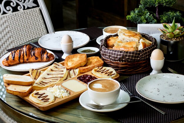 Xícara de capuccino quente e croissant de chocolate com café da manhã