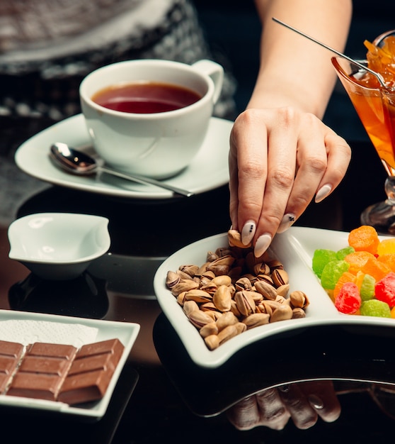 Xícara de chá branca servida com chocolate, pistache