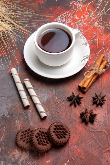 Xícara de chá com biscoitos de chocolate sobre biscoitos escuros de mesa