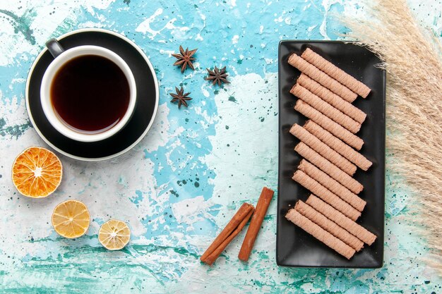 Xícara de chá com biscoitos e canela na superfície azul da vista superior