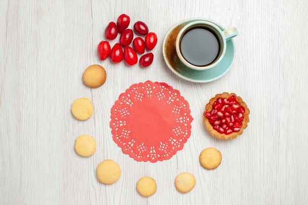 Xícara de chá com biscoitos e frutas em uma mesa branca chá fruta sobremesa bolo com vista de cima