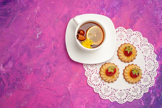 Xícara de chá com biscoitos na mesa rosa doce cor de chá