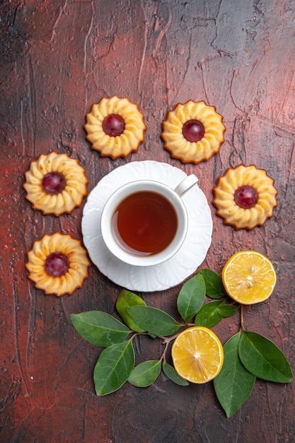 Xícara de chá com bolinhos na mesa escura de sobremesa doce de biscoito