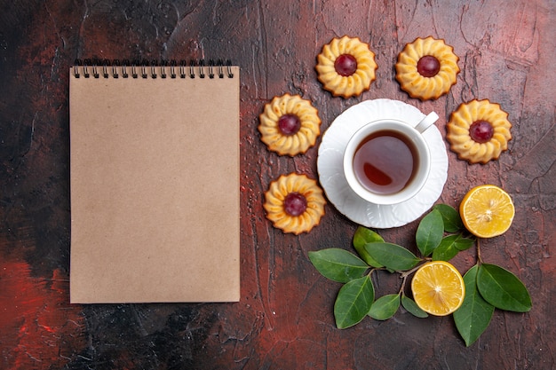 Xícara de chá com bolinhos na mesa escura sobremesa biscoito doce