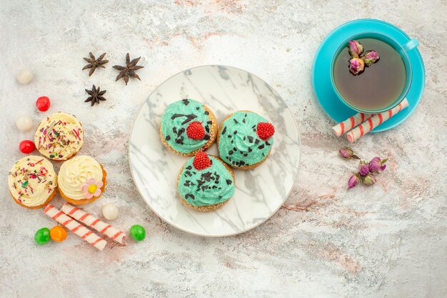 Xícara de chá com bolos de creme na superfície branca chá sobremesa bolacha torta de vista superior