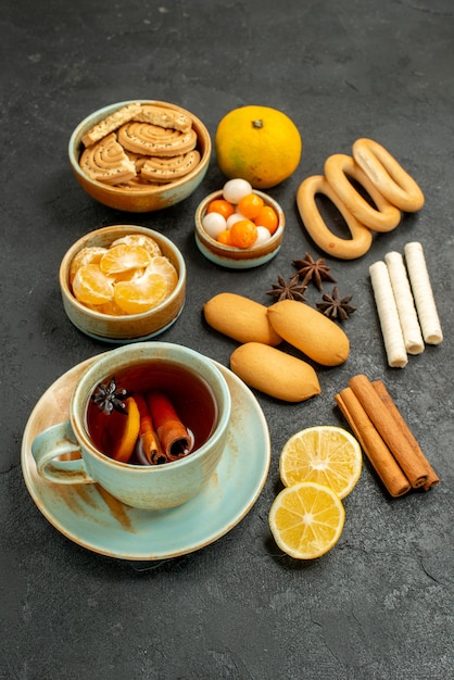 Xícara de chá com doces, biscoitos e frutas na mesa cinza biscoito doce de chá