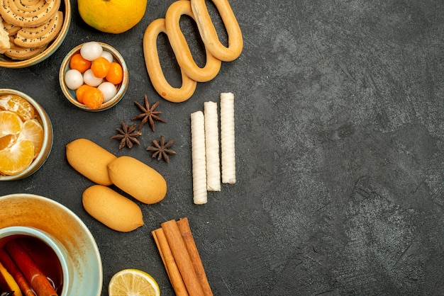 Foto grátis xícara de chá com doces, biscoitos e frutas na mesa cinza biscoito doce de chá