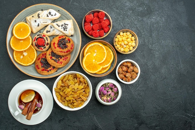 Foto grátis xícara de chá com doces, nozes e fatias de laranja na superfície escura confiture chá doce