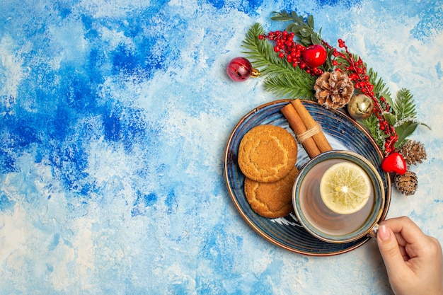 Xícara de chá com fatias de limão, biscoitos de canela em pau de canela em pires na mesa azul com lugar grátis