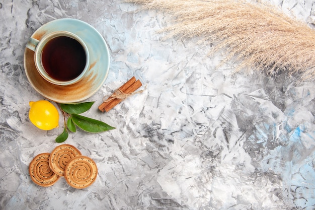 Xícara de chá com limão e biscoitos na mesa branca bebida chá de frutas com vista de cima