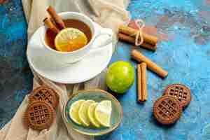 Foto grátis xícara de chá com limão e canela, biscoitos xale bege e limão na mesa vermelha