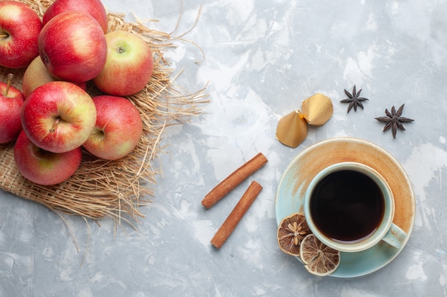 Xícara de chá com maçãs vermelhas e canela na mesa branca de cor doce