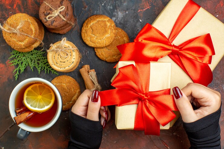 Foto grátis xícara de chá com sabor de limão e canela diferentes biscoitos amarrados com corda na mesa vermelha escura vista de cima