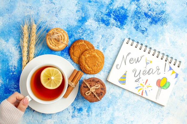 Xícara de chá de ano novo escrita em biscoitos de bloco de notas na mesa azul com vista de cima