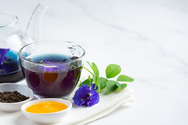Xícara de chá de flor de ervilha borboleta com mel na mesa