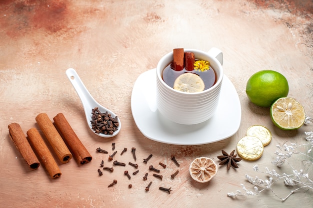 Foto grátis xícara de chá de frente para o chá com limão e canela no chá marrom claro de biscoito de limão