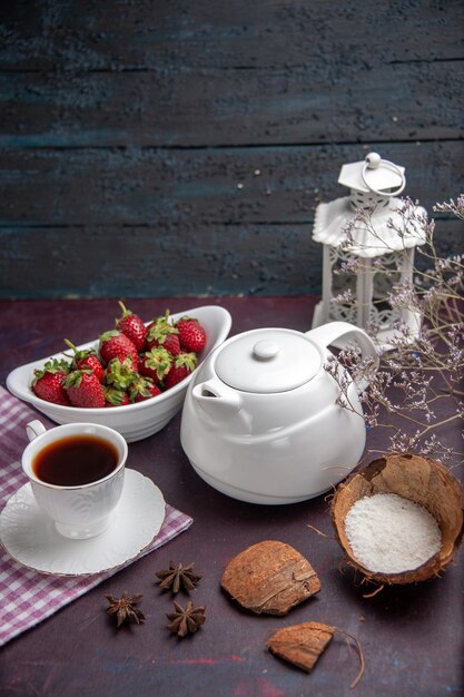 Xícara de chá de frente para o chá com morangos na superfície escura bebida de chá de cor de fruta