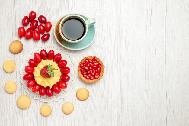 Xícara de chá de vista de cima com bolo cremoso e frutas na mesa branca