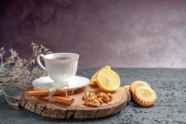 Xícara de chá de vista frontal com limão e biscoitos em fundo escuro