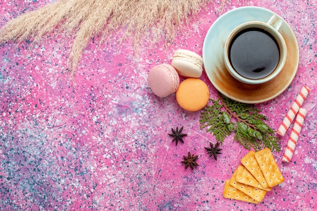 Xícara de chá de vista superior com biscoitos e macarons na superfície rosa