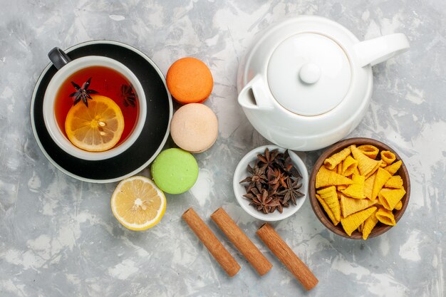 Xícara de chá de vista superior com macarons franceses e canela na superfície branca