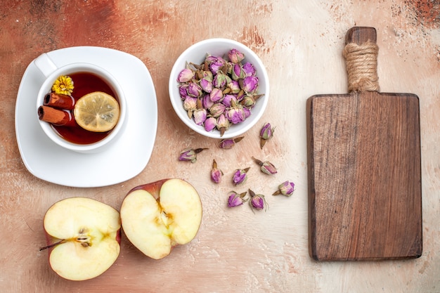 Xícara de chá de vista superior com maçãs e flores em flor de chá de frutas de piso claro