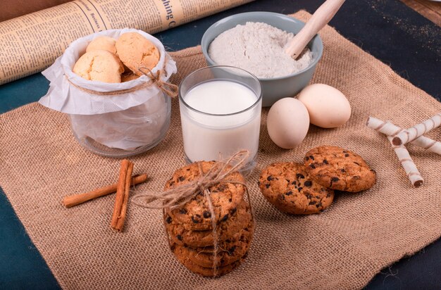 Xícara de leite e farinha com pote de biscoitos e ovo