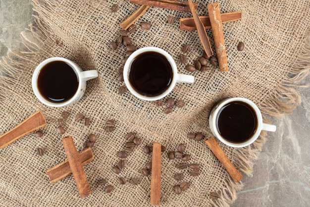 Xícaras de café, paus de canela e grãos de café na serapilheira