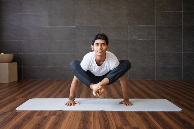 Yogi experiente fazendo vaga-lume pose variação no ginásio
