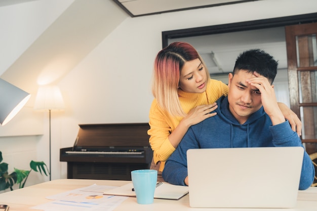 Foto grátis young salientou casal asiático gerenciando as finanças, revendo suas contas bancárias usando o computador portátil