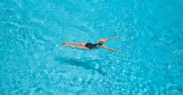 Foto grátis zenith uma vista do alto de uma linda loira adulta em um maiô preto nadando em uma piscina azul lazer e tempo de férias uma vista da piscina com uma mulher europeia nadando