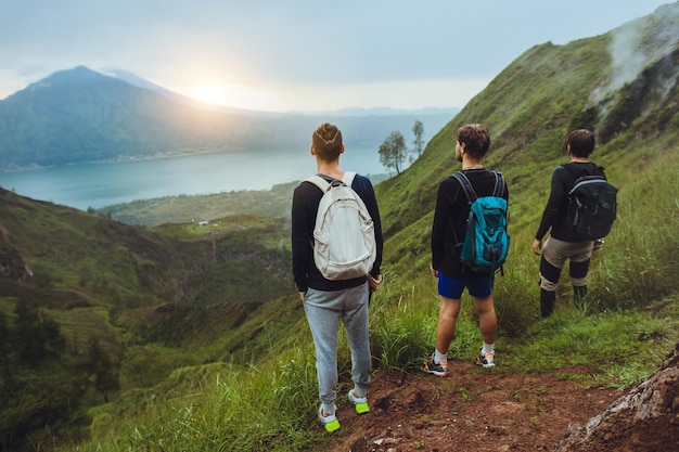 3 Wanderer, der den Sonnenaufgang auf dem Berg betrachtetFreiheitskonzept Aufstieg zum VulkanReiseführerAusrüstung