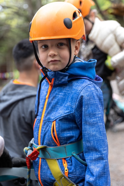 Abenteuer Kletterhochseilpark - kleiner Junge auf Kurs in Berghelm und Sicherheitsausrüstung