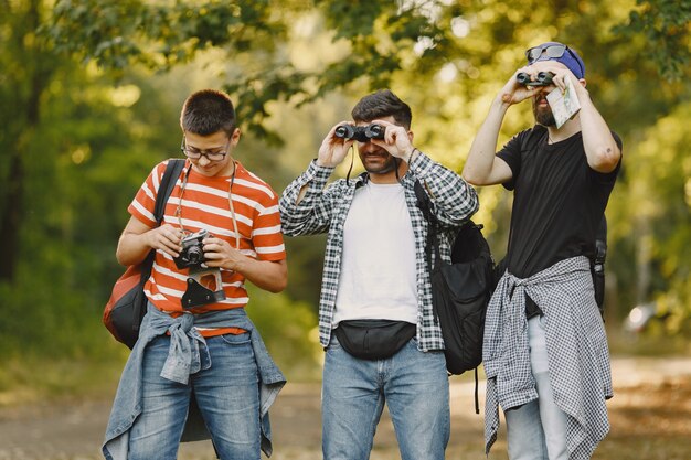 Abenteuer-, Wander- und Personenkonzept. Gruppe lächelnder Freunde in einem Wald. Mann mit Fernglas.