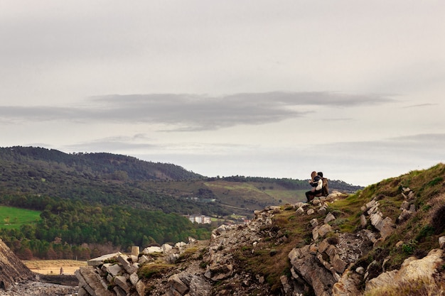 Abenteuerliches romantisches Wanderpaar, das auf den Felsen sitzt und die Berge betrachtet